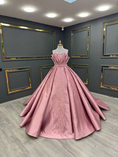 a pink ball gown is on display in a room with gray walls and gold trimmings