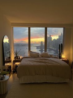 a bedroom with a large window overlooking the water and cityscape in the distance