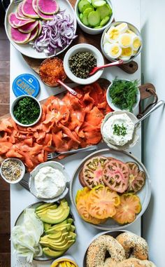 an assortment of food is laid out on a white counter top with bowls and spoons