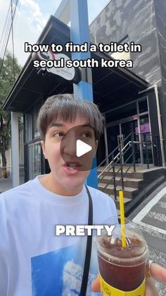 a person holding a drink in front of a building with the caption how to find a toilet in seoul south korea