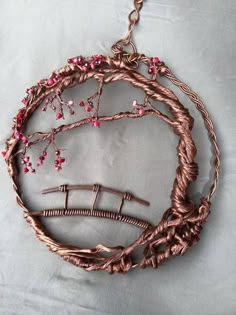 a piece of art made out of wire and wood with pink flowers on the top