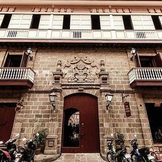 motorcycles are parked in front of a building with balconies on the second floor