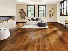 a living room with wood flooring and large windows in the corner, along with a white couch