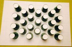 several white and black cups are arranged on a sheet of paper with one green dot in the middle