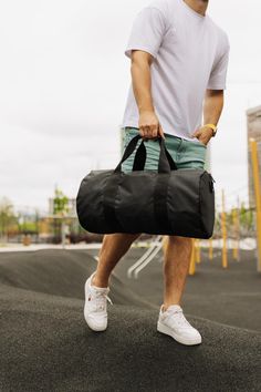 a man carrying a black duffel bag on top of a skateboard ramp