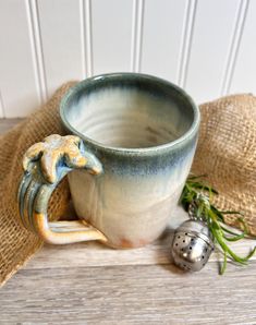 a ceramic mug sitting on top of a wooden table next to a burlock