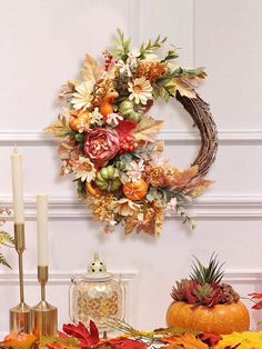 a wreath is hanging on the wall next to some candles and other autumn decor items