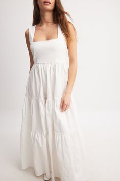 This maxi dress is stretchy and made of cotton and features a flowy fit. It has a square neckline and a hidden side zipper. The maxi dress has gathered seams at the bottom half. Chic Square Neck Maxi Dress, Chic Solid Color Maxi Dress With Square Neck, White Midi Dress With Ruched Detail And Straight Neckline, White Ruched Midi Dress With Straight Neckline, White Ruched Cotton Midi Dress, White Cotton Ruched Midi Dress, Cotton Midi Dress With Ruched Square Neck, Cotton Midi Dress With Square Neck And Ruched Detail, Spring Cotton Maxi Dress With Square Neck