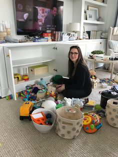 a woman sitting on the floor surrounded by toys