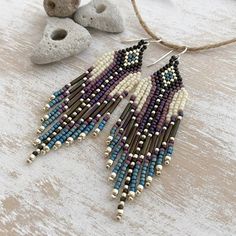 a pair of beaded earrings sitting on top of a wooden table next to rocks