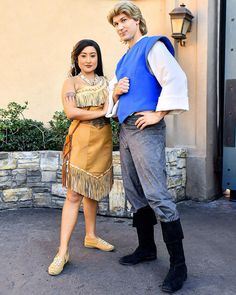 a man and woman dressed in native american clothing standing next to each other on the street