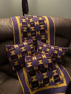 purple and yellow quilted pillows sitting on top of a couch