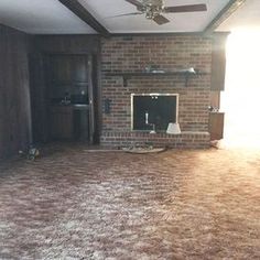 an empty living room with brick fireplace and ceiling fan