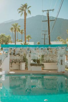 an empty swimming pool with palm trees and mountains in the backgroung area