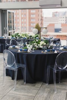 the table is set up with clear chairs and blue linens for an elegant dinner