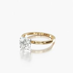 a yellow gold engagement ring with a single diamond in the center, on a white background