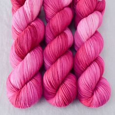 three skeins of pink yarn sitting next to each other on a white surface