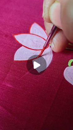 someone cutting out paper flowers with scissors on a pink tablecloth that's being sewn