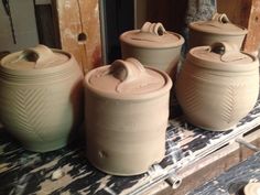 three clay jars sitting on top of a wooden table