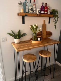 three stools sit at the bar with bottles on shelves above them and plants in vases