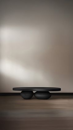 two black round tables sitting on top of a wooden floor in front of a gray wall