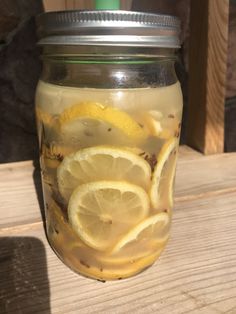 a mason jar filled with lemon slices on top of a wooden table