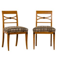 two wooden chairs with patterned upholstered seat cushions on each side, one in wood and the other in fabric