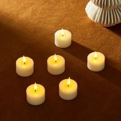 six lit candles sitting on top of a brown carpet