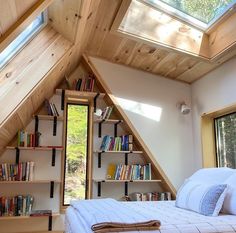 an attic bedroom with skylights and bookshelves on the wall, along with a bed