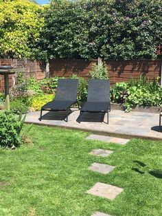 two lawn chairs sitting on top of a lush green field