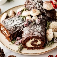 there is a chocolate roll on the plate with nuts and greenery in front of it