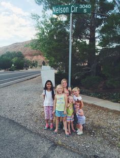 four children standing in front of a street sign on nelson cir coo road