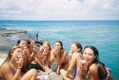 a group of young women sitting next to each other near the ocean