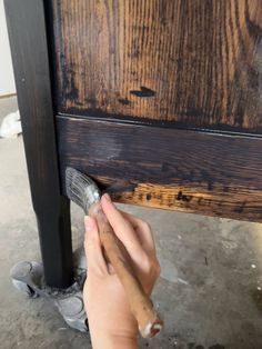 someone using a brush to paint the top of a wooden table with dark brown stain