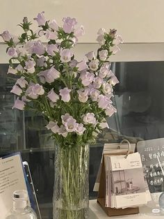 a vase filled with pink flowers sitting on top of a table next to a book