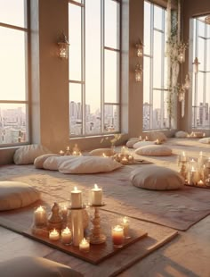 a room filled with lots of candles and pillows on top of floor next to large windows