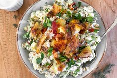 a white bowl filled with potato salad on top of a wooden table next to a fork