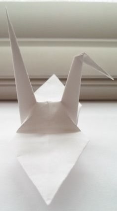 an origami bird sitting on top of a window sill