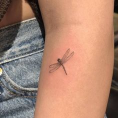 a small dragonfly tattoo on the arm