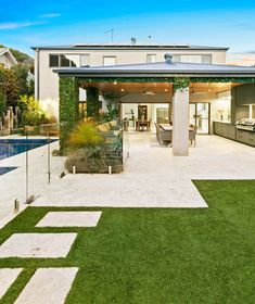 an outdoor living area with grass and plants on the lawn next to a swimming pool