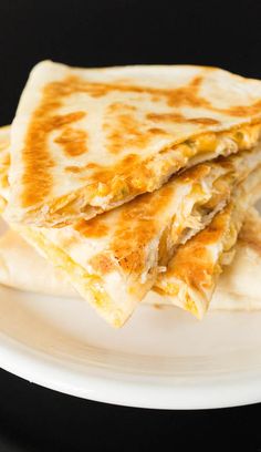 two quesadillas stacked on top of each other on a white plate against a black background