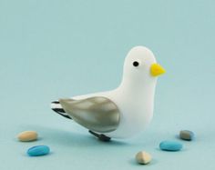 a small white bird sitting on top of blue and white rocks with one eye open