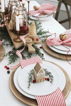 a table set for christmas with plates, candles and napkins on the place settings