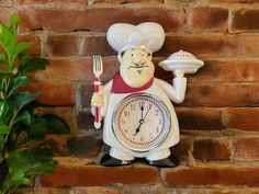 a clock with a chef holding a fork and knife on top of a brick wall