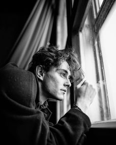 black and white photograph of a man looking out the window