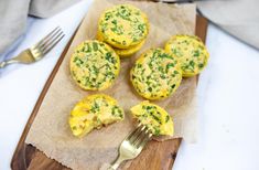 four mini quiches on a cutting board with a fork and napkin next to them