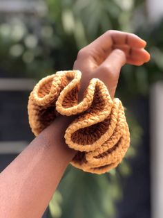 a woman's hand holding a crocheted object in the shape of a spiral