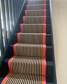 the stairs are lined with black and white striped rugs, along with orange trim