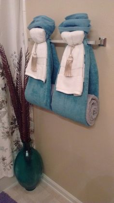 two towels hanging on a towel rack next to a vase with flowers and plants in it