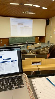 an open laptop computer sitting on top of a desk in front of a class room